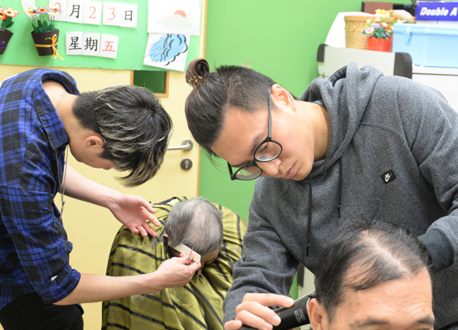 The number of elders participating in the free haircut activity is more than expected. Even social worker Cheung Kin-hei (right) became Ka-ho’s ‘assistant’.