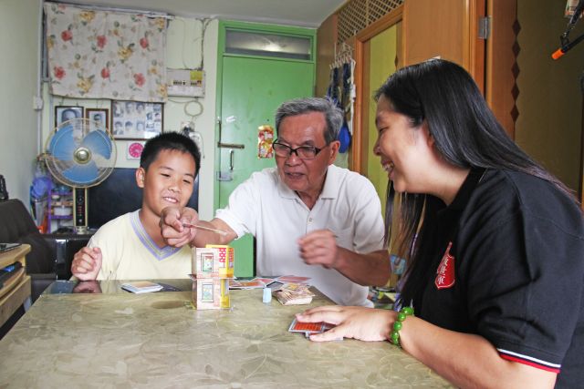 Social worker guides Grandpa and Chong to play fun family games, creating happy memories.