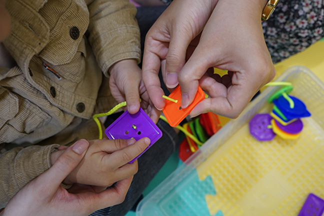 Threading buttons, one of the lessons in the SKY curriculum, is a good hand-eye coordination training for children.